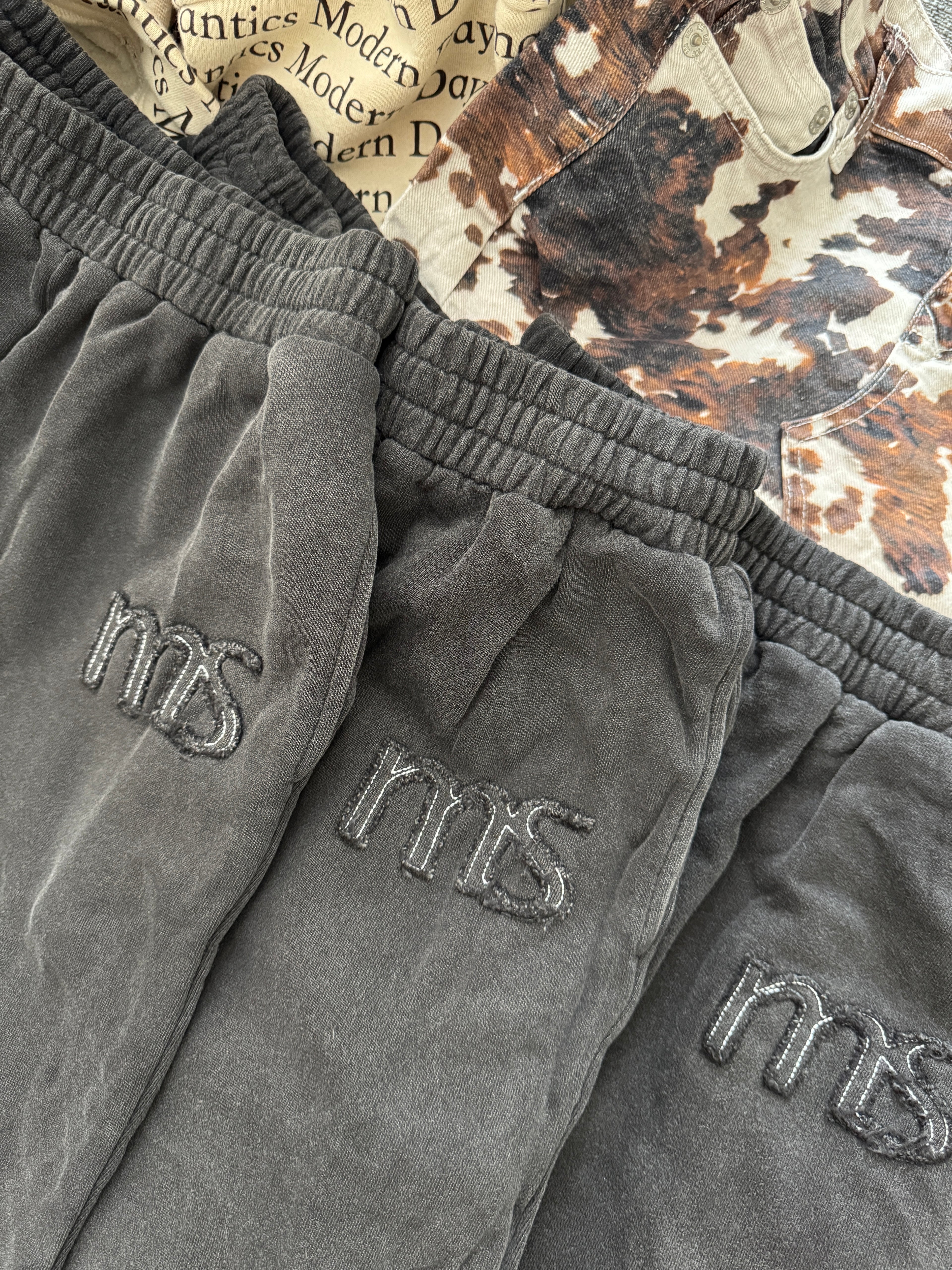 Gray sweatpants with 'MS' branding on a textured surface